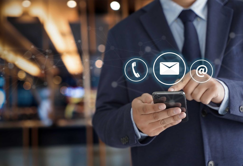 A man in a suit holding a phone and looking at it.