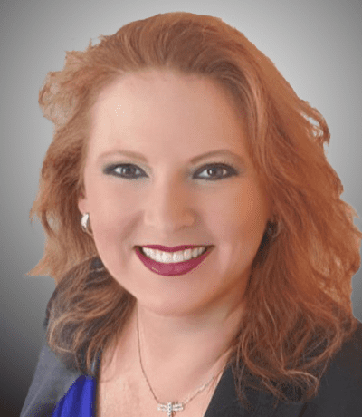 A woman with red hair and blue eyes smiling.